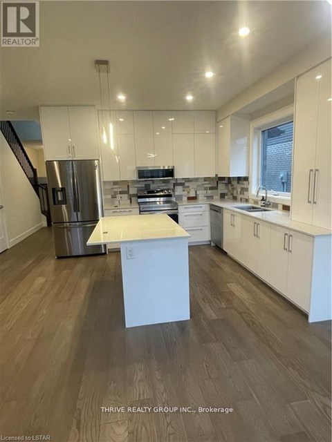 A kitchen with white cabinets and a wooden floor.