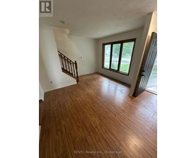 A room with wooden flooring and a staircase.