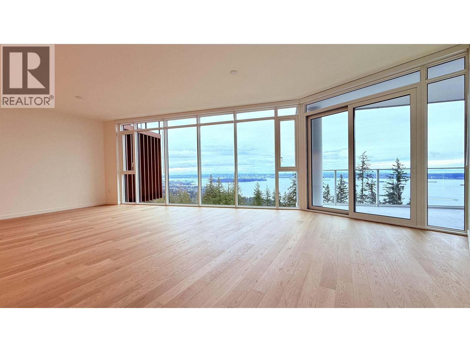 A large empty room with a view of the ocean through the windows.
