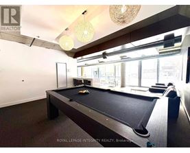 A pool table in a room with a high ceiling and a chandelier.