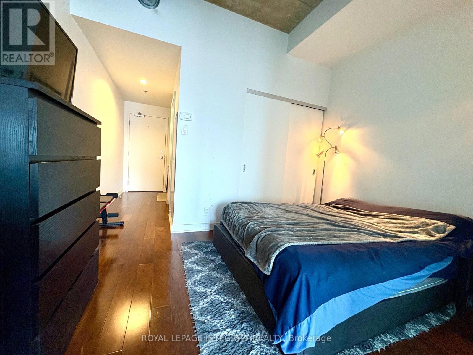 A bedroom with a bed, dresser, and lamp.