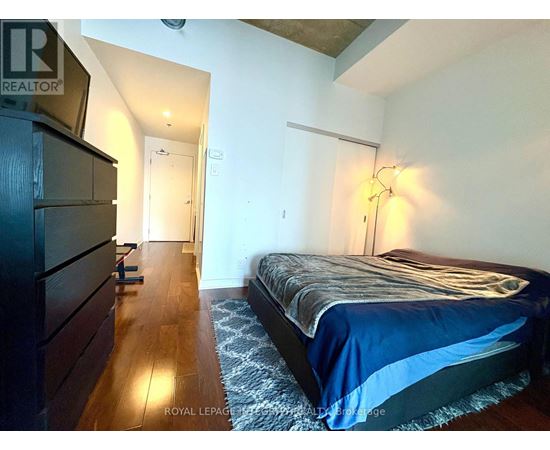 A bedroom with a bed, dresser, and lamp.