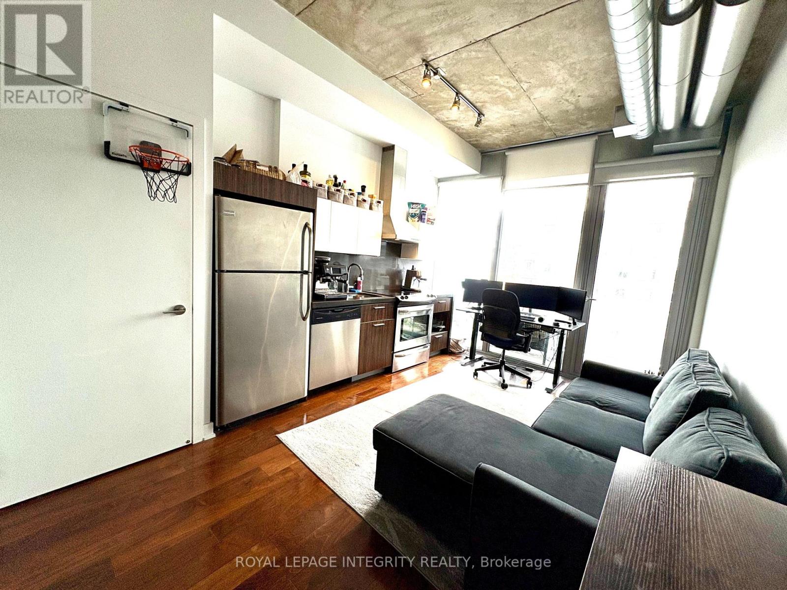 A modern kitchen with a black couch and a basketball hoop on the wall.