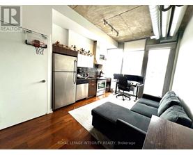 A modern kitchen with a black couch and a basketball hoop on the wall.
