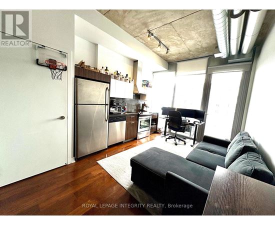 A modern kitchen with a black couch and a basketball hoop on the wall.