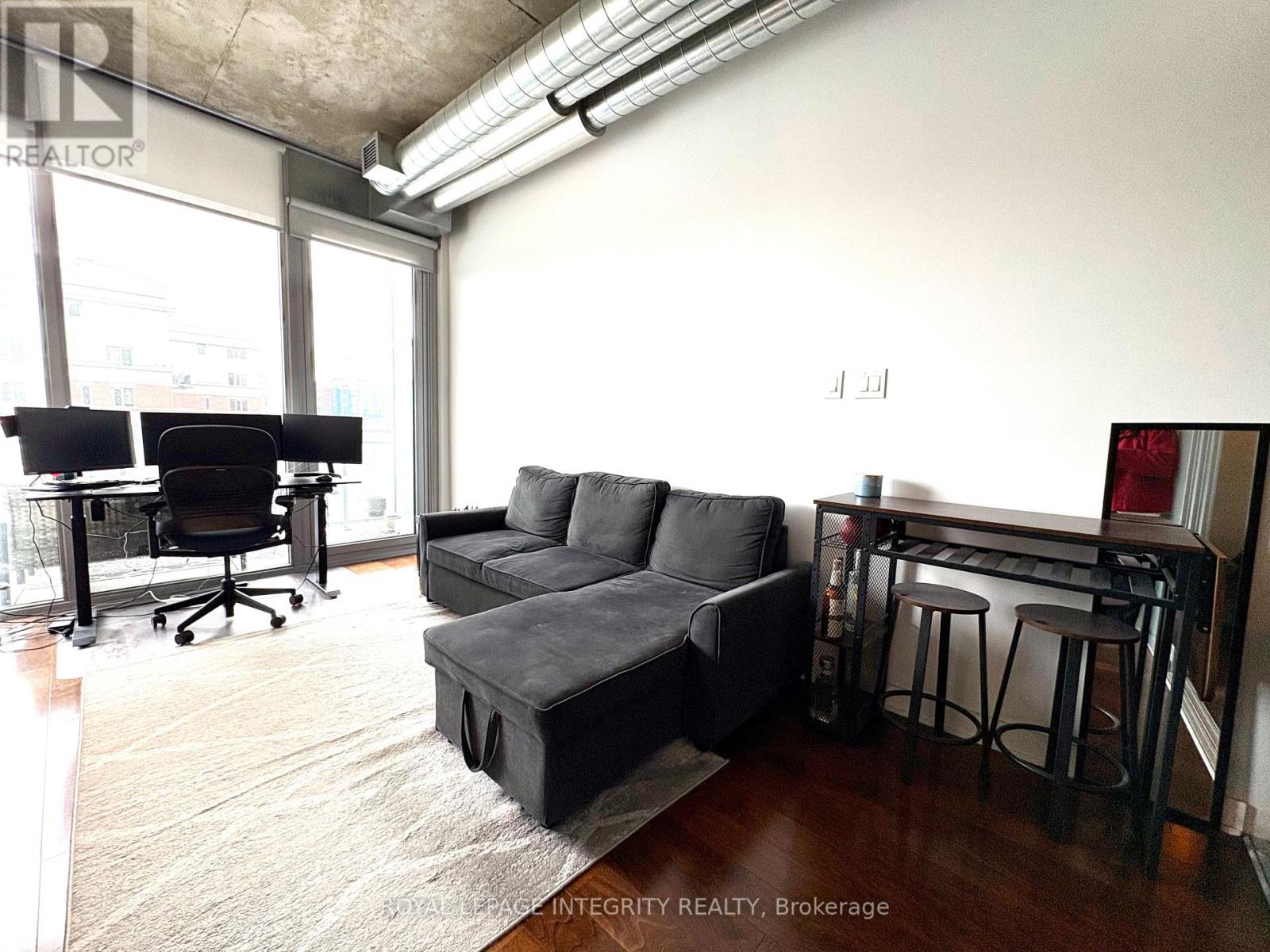 A living room with a black couch and a black desk.