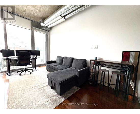A living room with a black couch and a black desk.