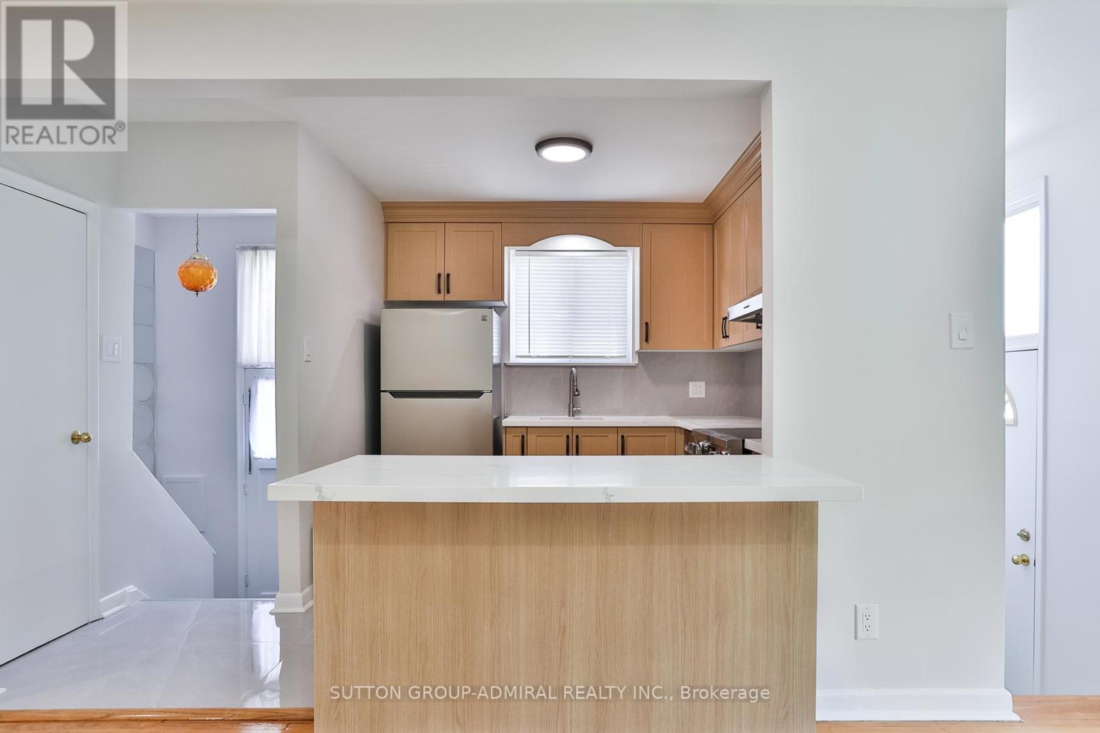 A kitchen with a white counter top and wooden cabinets.