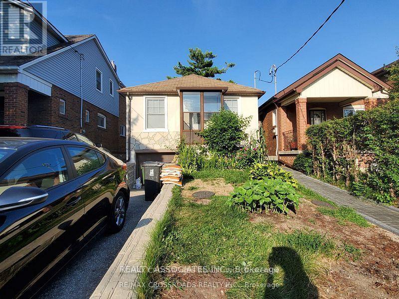 A black car is parked on a driveway in front of a house.
