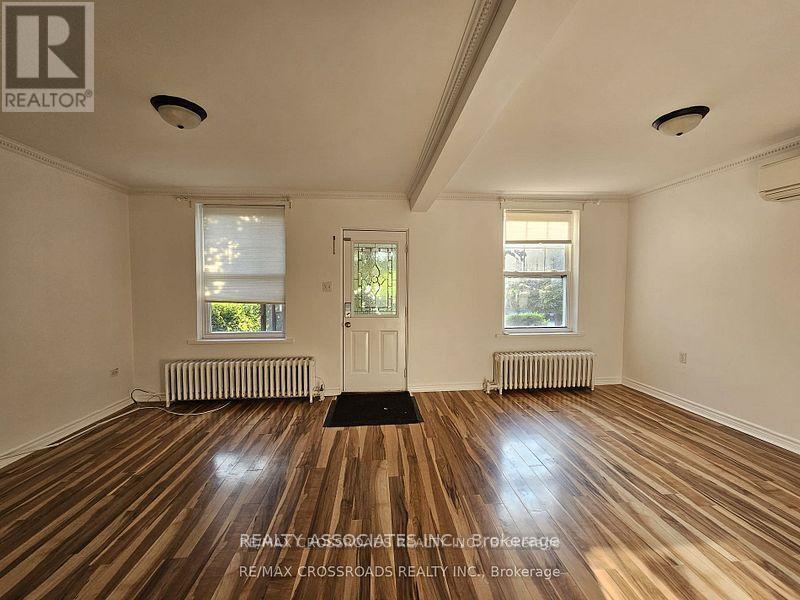 A room with wooden floors and white walls, with a door in the center.