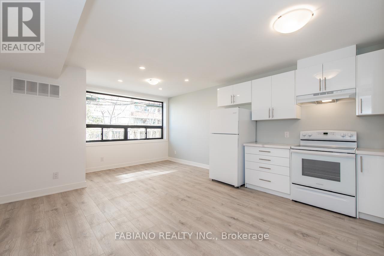 A white kitchen with wood flooring and a large window.