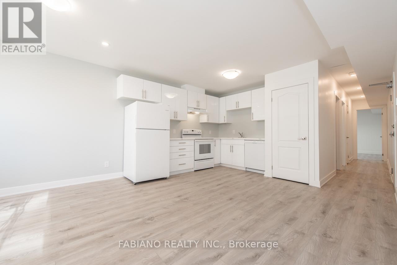 A spacious kitchen with white cabinets and a wooden floor.
