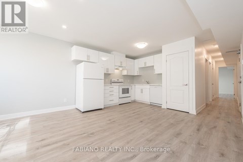 A spacious kitchen with white cabinets and a wooden floor.