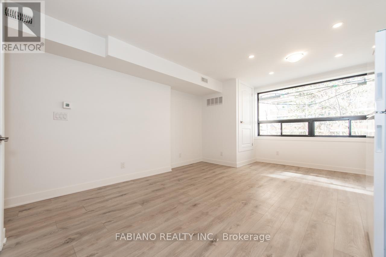 A spacious room with wooden flooring and a large window.