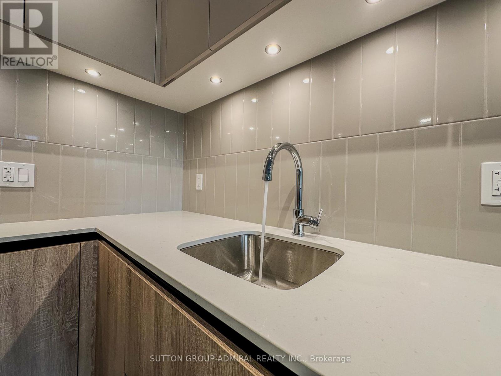 A modern kitchen with a stainless steel sink and a wooden cabinet.