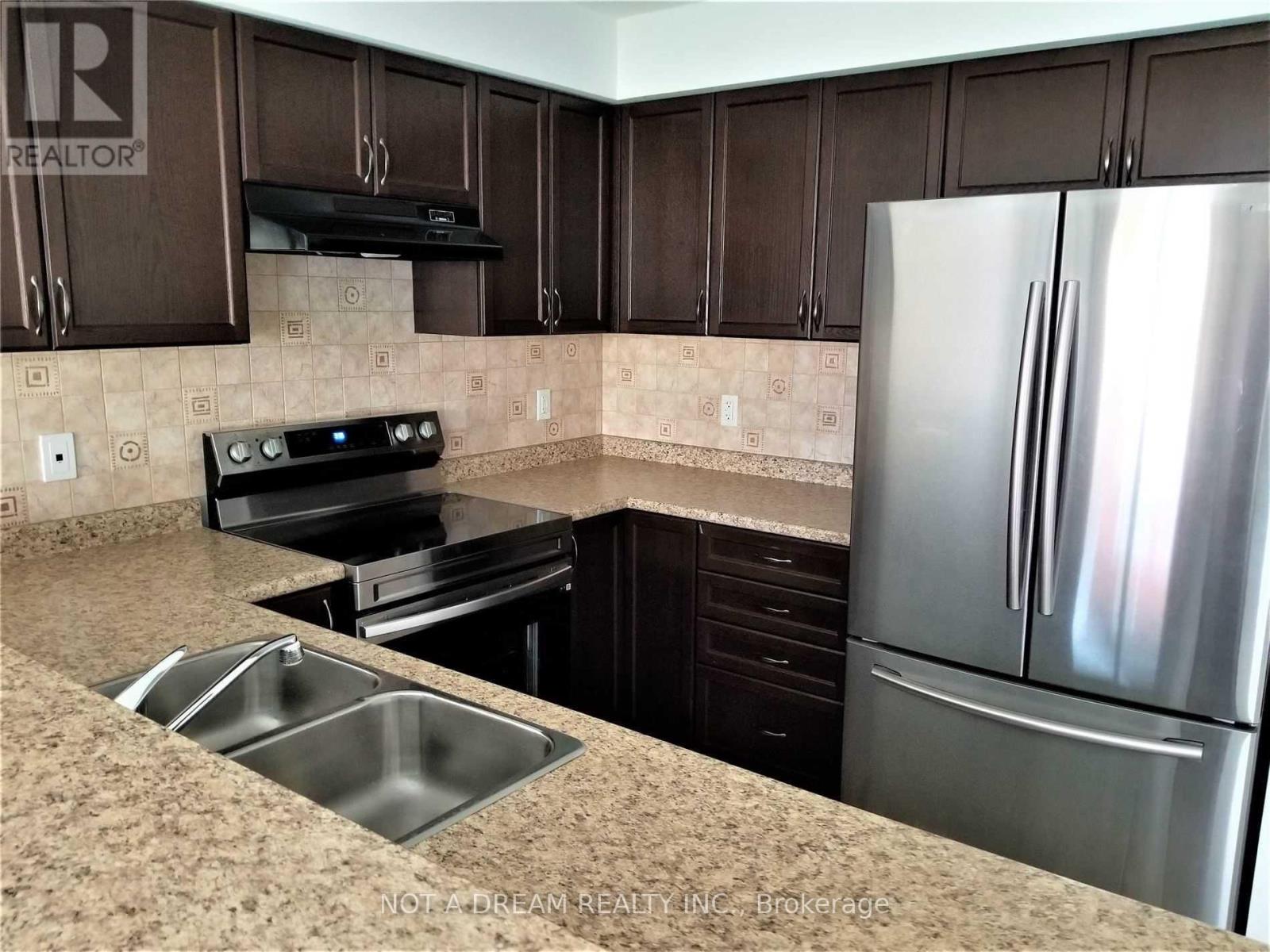 A kitchen with brown cabinets and a stainless steel refrigerator.