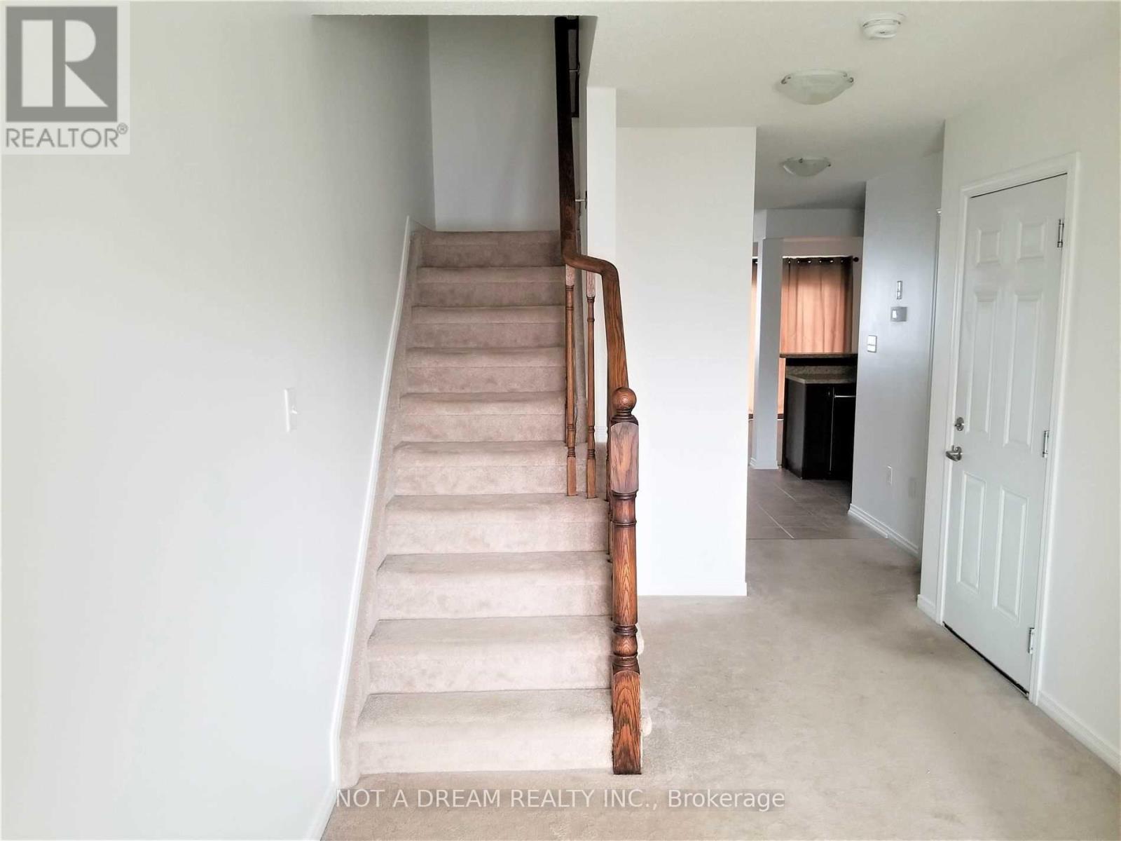 A staircase with a wooden handrail leads to a bedroom.