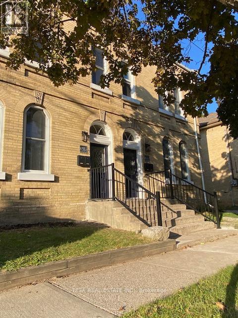 A brick building with a black iron railing on the steps.