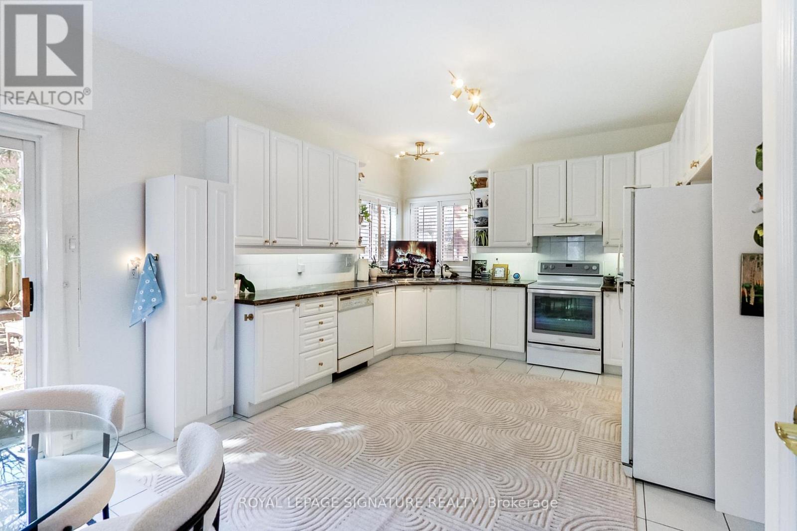 A white kitchen with a glass table and chairs.