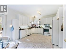 A white kitchen with a glass table and chairs.