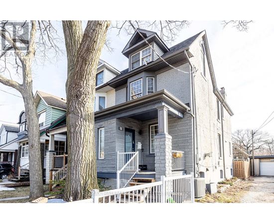 A grey house with a white picket fence in front.