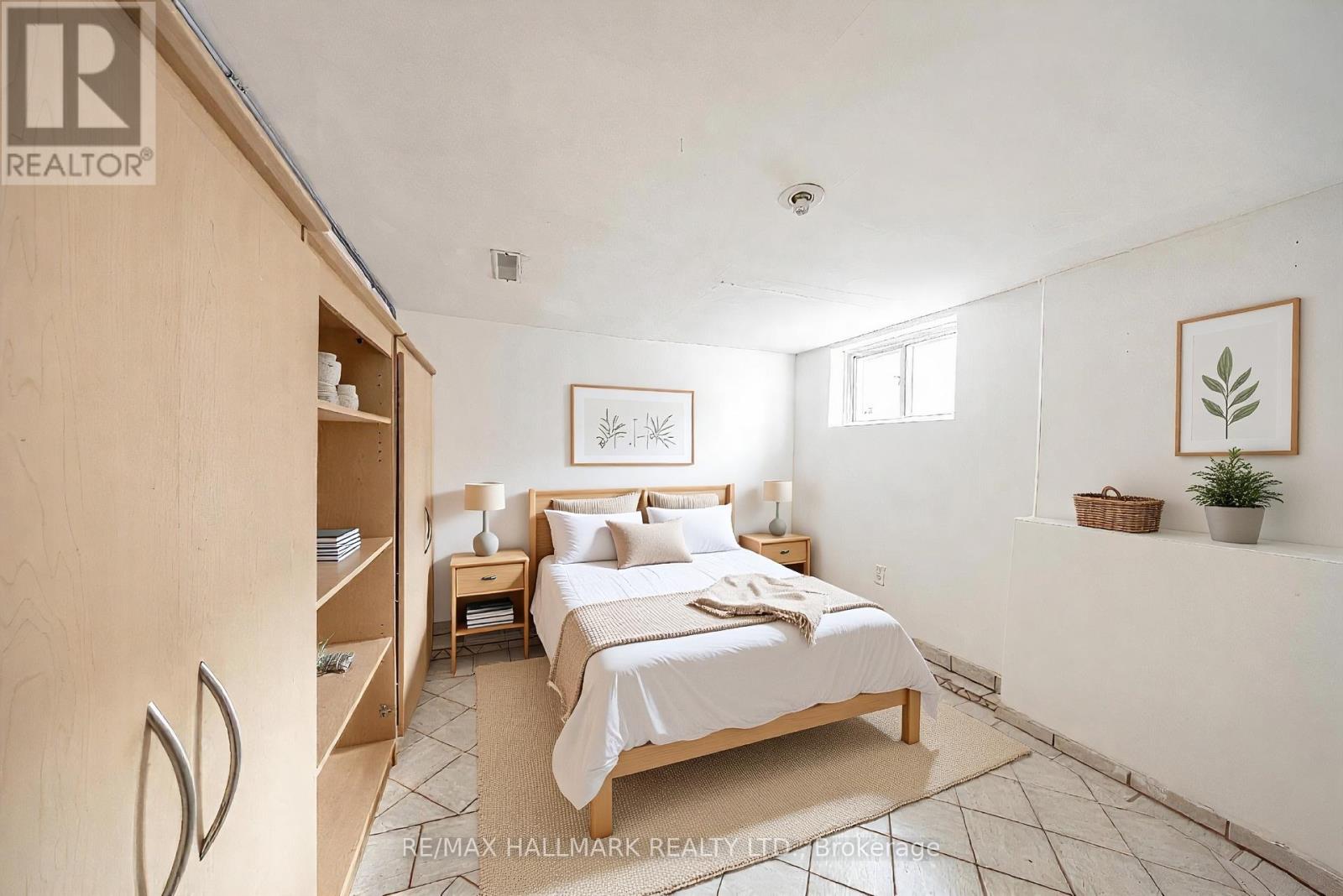 A bedroom with a bed, nightstand, and a plant.