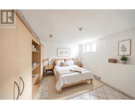 A bedroom with a bed, nightstand, and a plant.