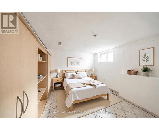 A bedroom with a bed, nightstand, and a plant.