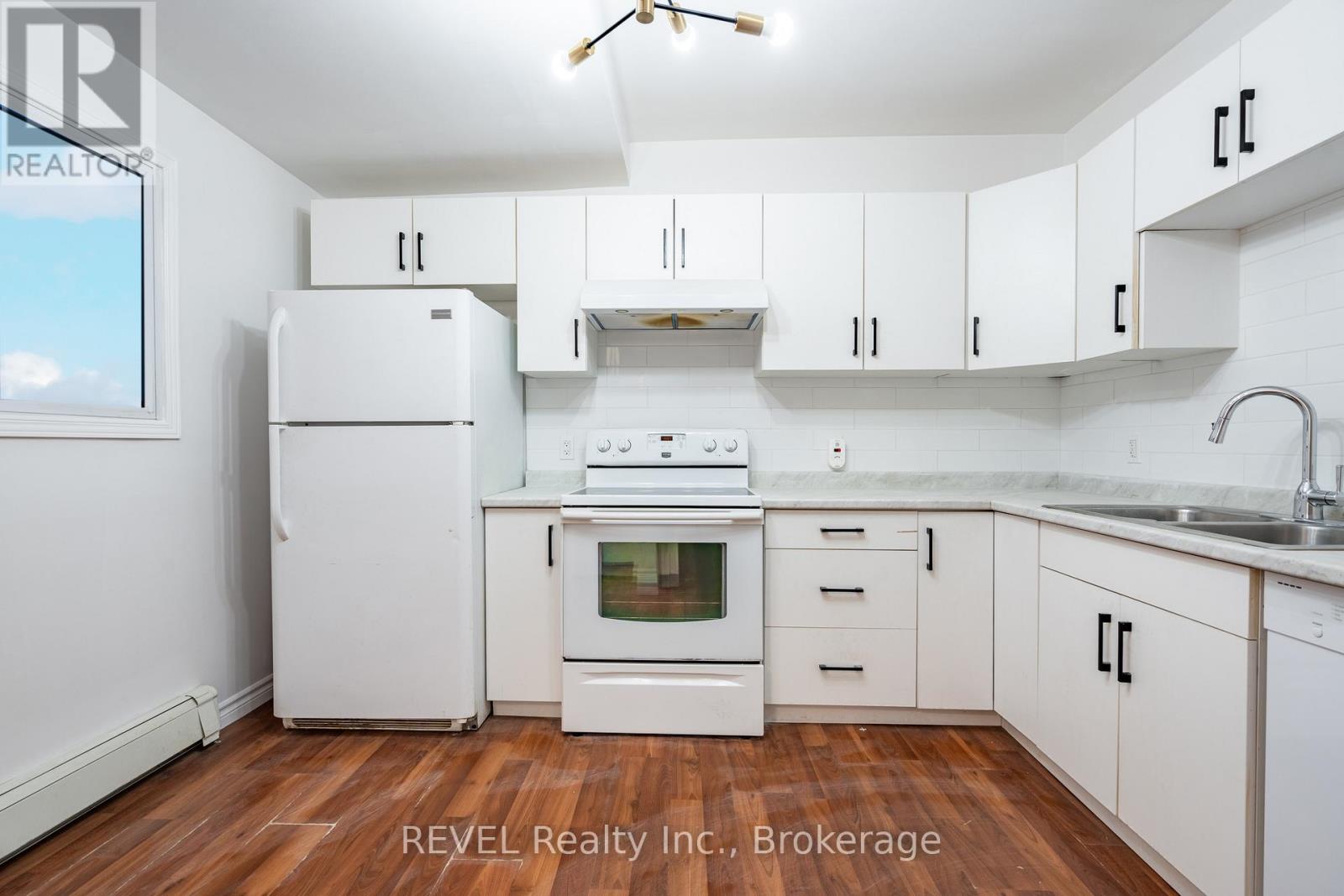 A white kitchen with wooden floors and white appliances.