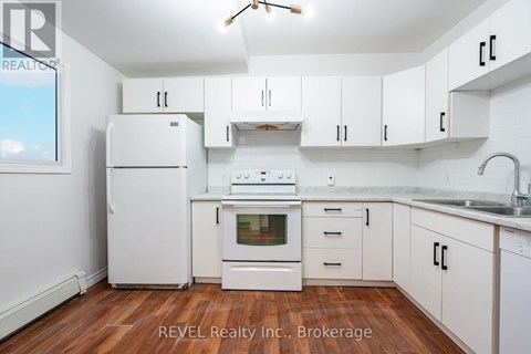 A white kitchen with wooden floors and white appliances.