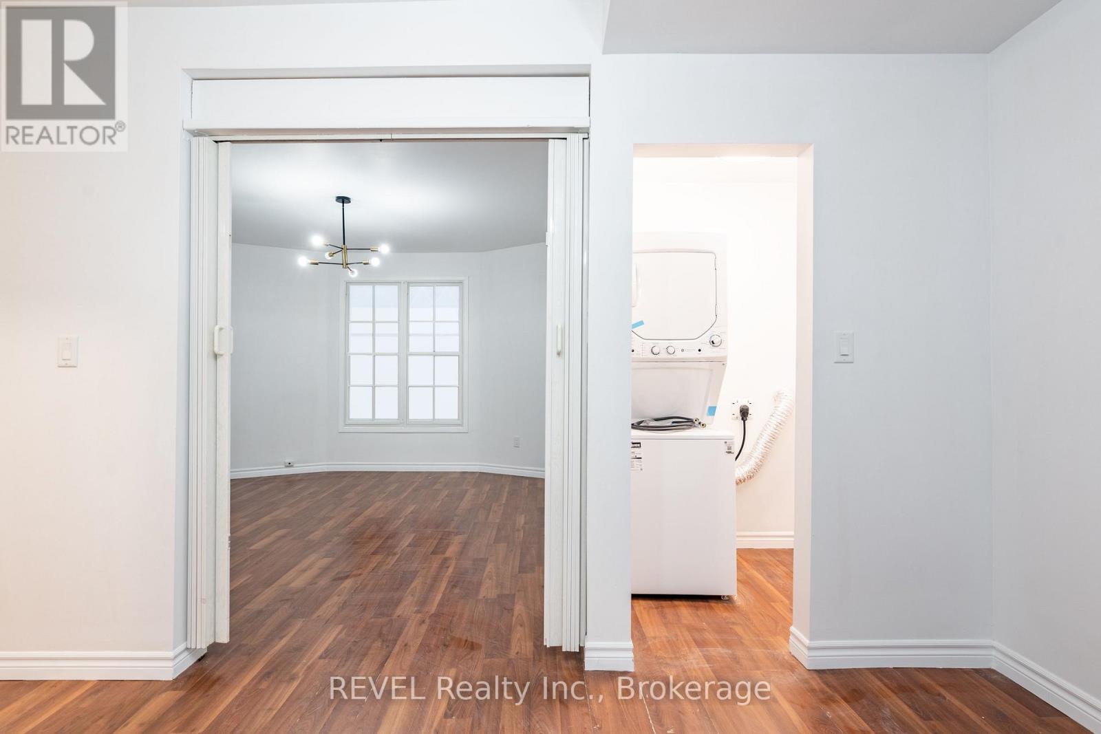 A room with a white fridge and a window.