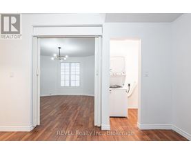 A room with a white fridge and a window.