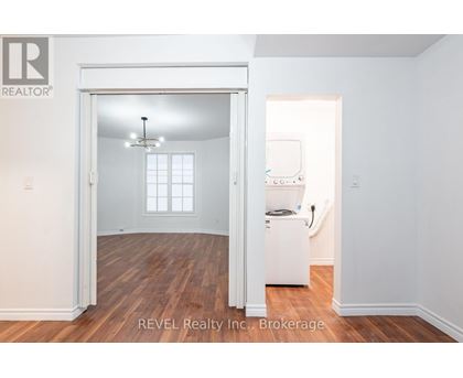 A room with a white fridge and a window.