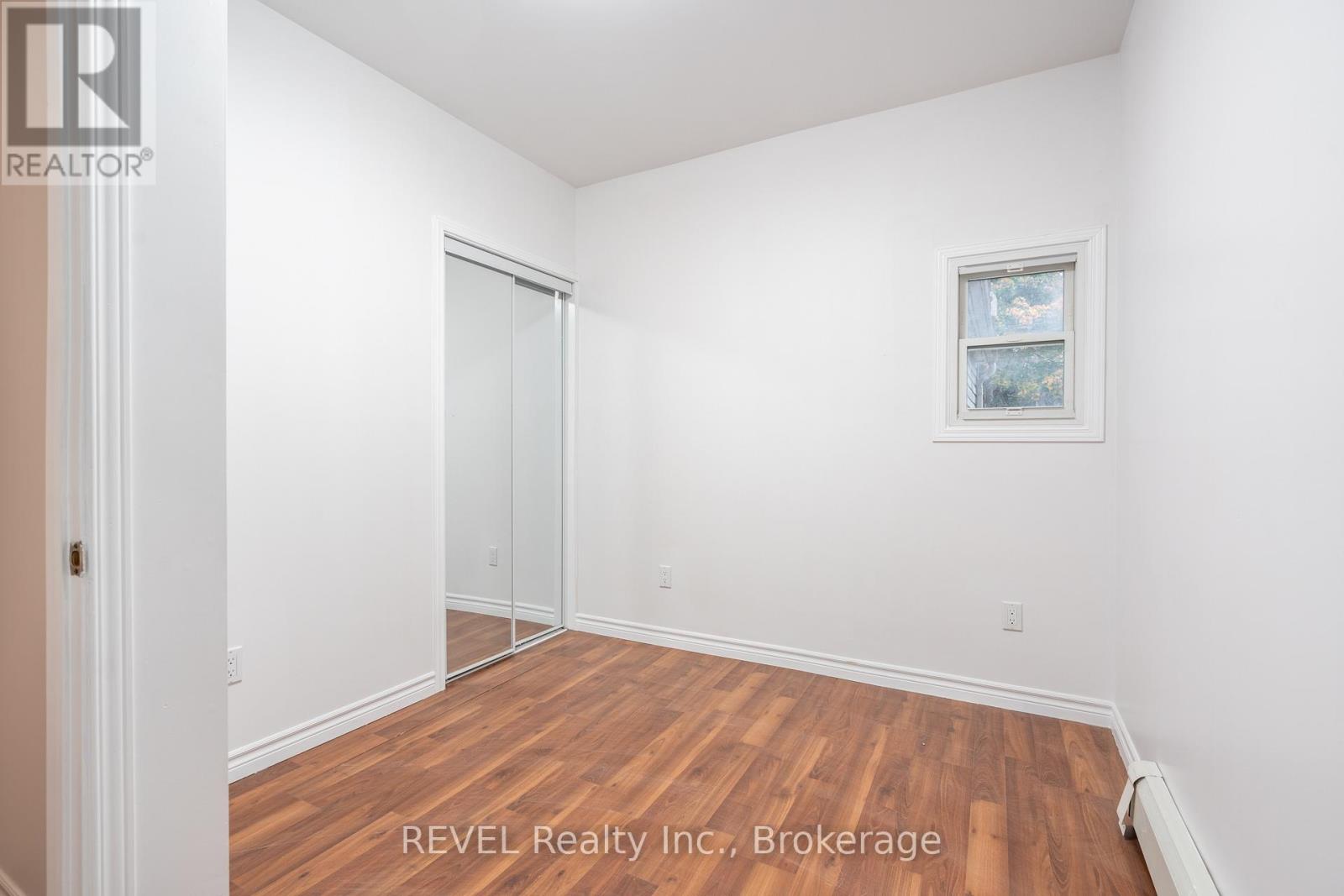 A room with a wooden floor and white walls, with a door and a window.