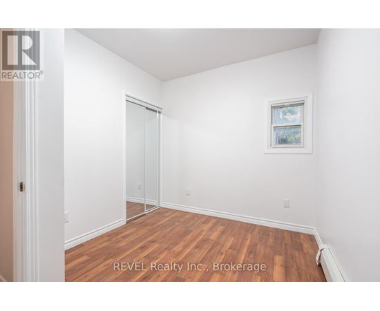 A room with a wooden floor and white walls, with a door and a window.