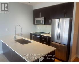 A kitchen with a sink, refrigerator, and microwave.