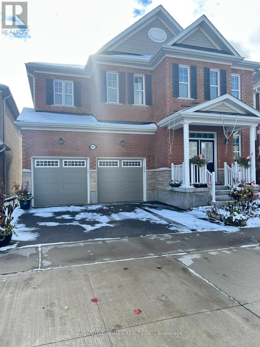 A large brick house with a white porch and two garage doors.