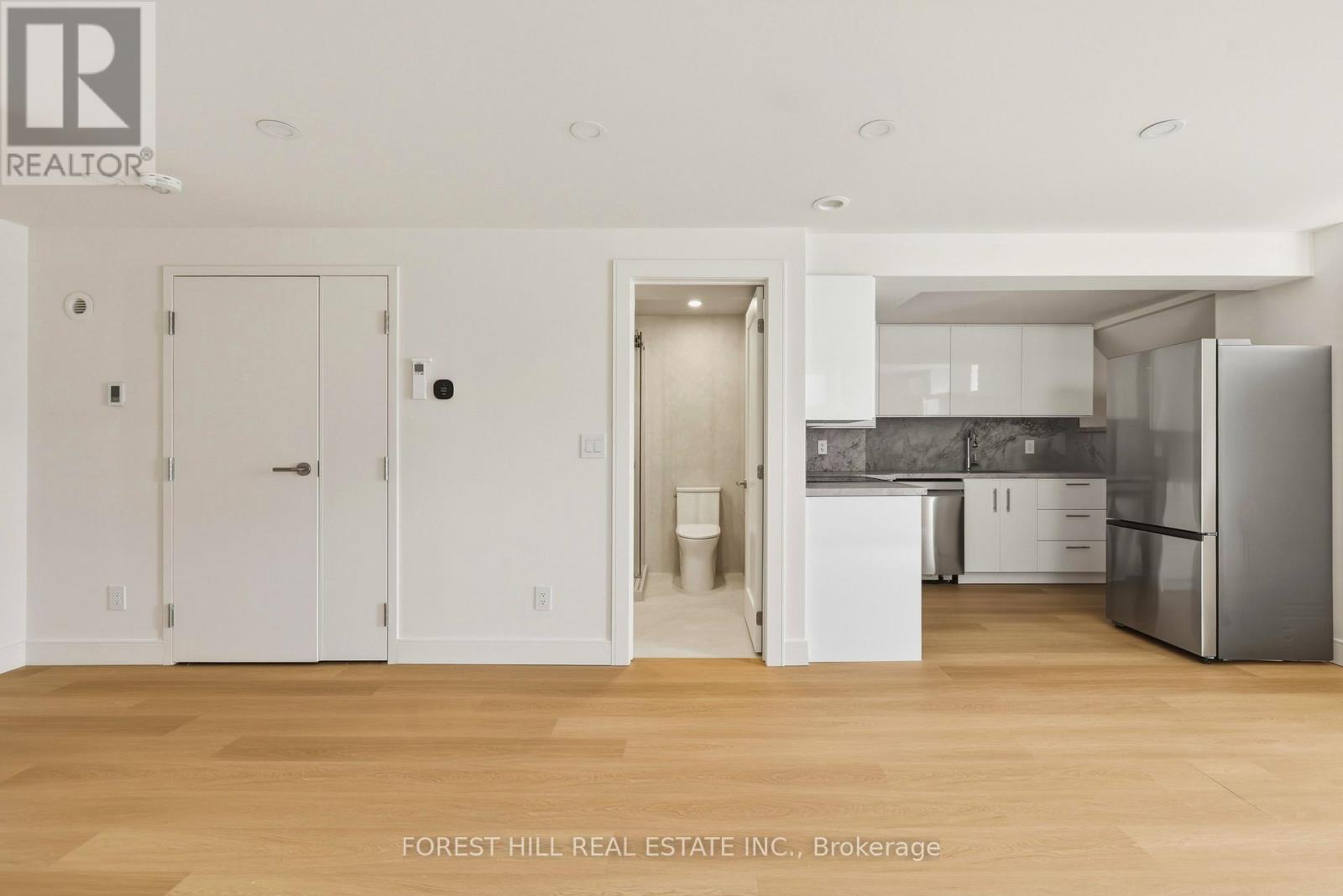 A kitchen with white cabinets and a refrigerator.