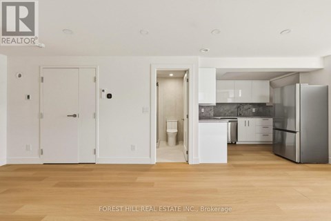 A kitchen with white cabinets and a refrigerator.