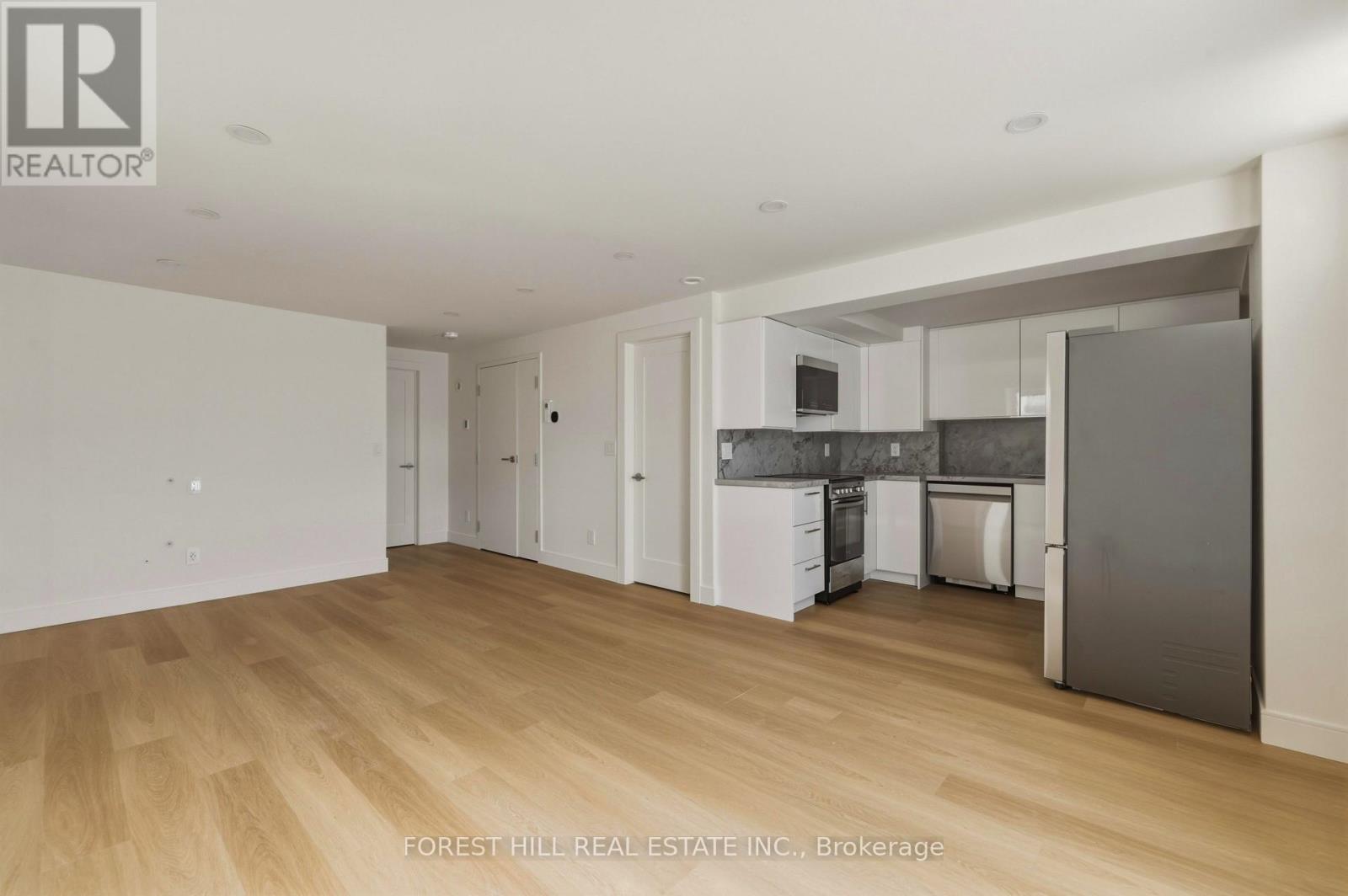 A kitchen area with a refrigerator, microwave, and cabinets.