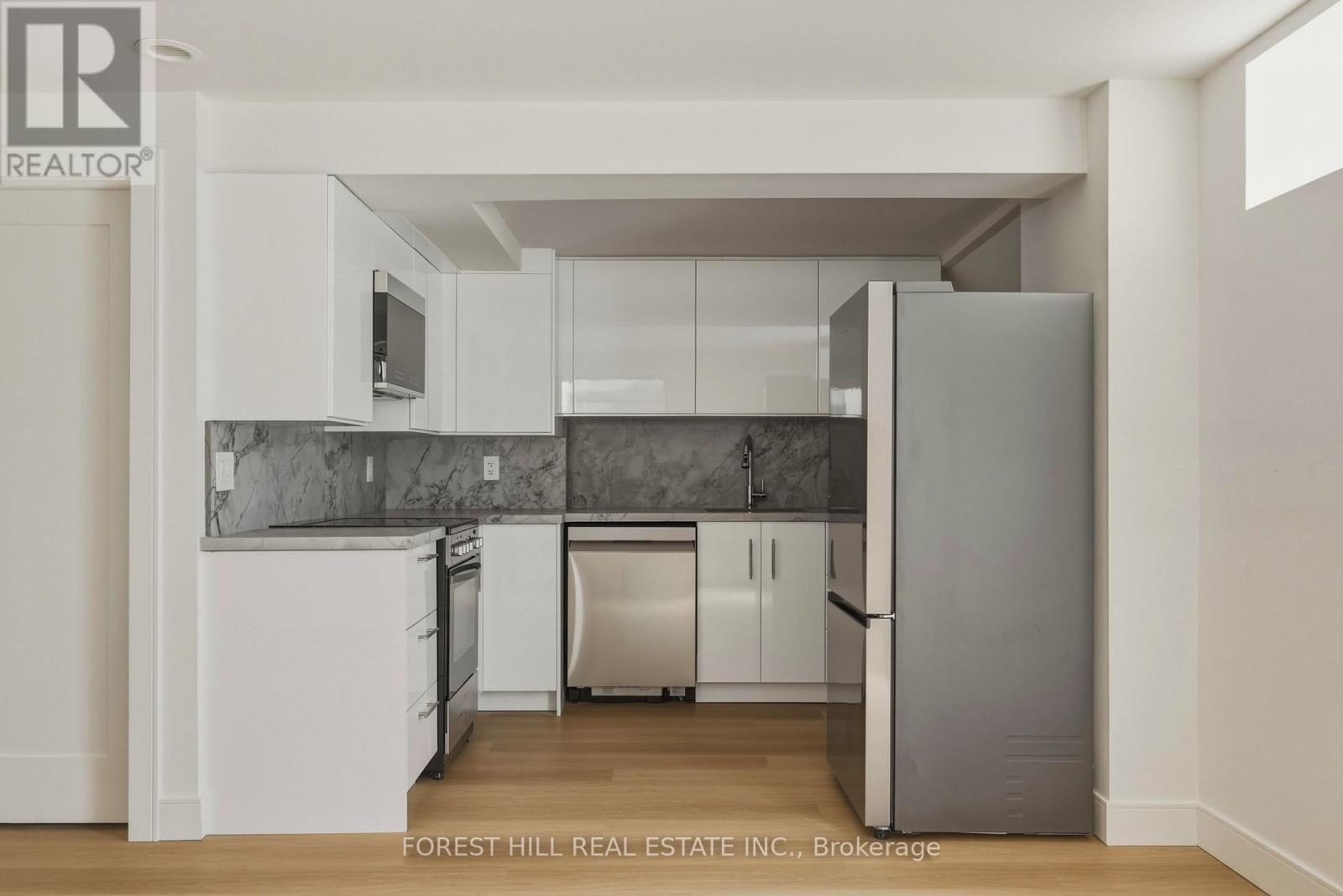 A kitchen with a refrigerator, sink, and cabinets.