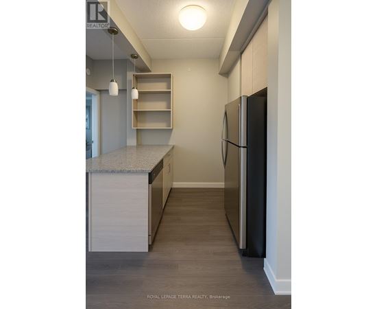 A kitchen with a black refrigerator and a granite counter top.