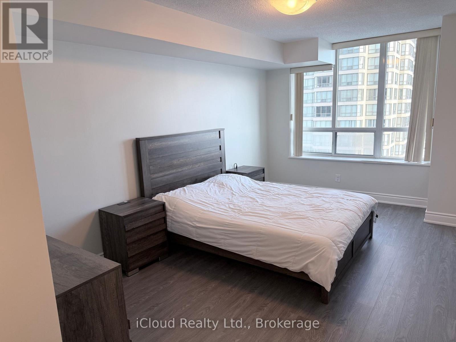 A bedroom with a bed, nightstand, and window.
