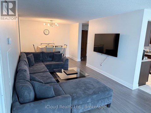 A living room with a grey sofa and a flat screen TV mounted on the wall.