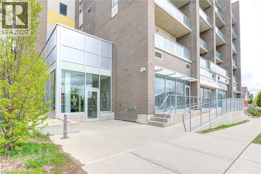 A modern building with glass doors and windows is surrounded by a sidewalk and a metal fence.