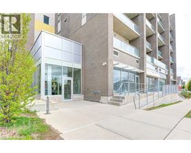 A modern building with glass doors and windows is surrounded by a sidewalk and a metal fence.