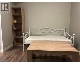 A bedroom with a white metal bed and a wooden table.