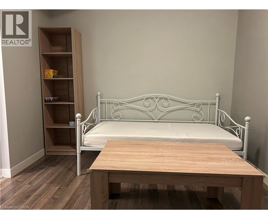 A bedroom with a white metal bed and a wooden table.