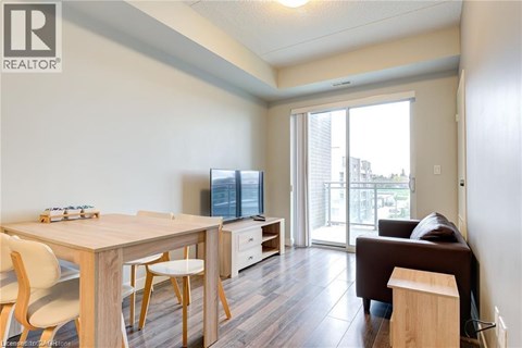 A living room with a brown couch and a dining table with chairs.