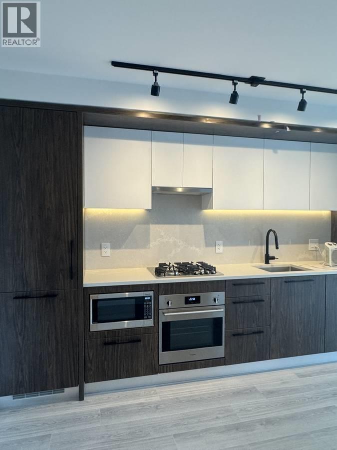 A modern kitchen with dark wood cabinets and stainless steel appliances.